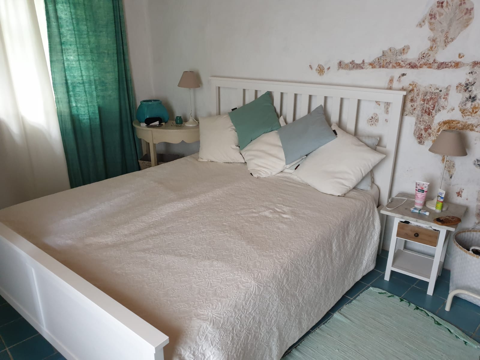 Ein gemütliches Doppelbett vor einer Wand mit den Resten alter Bemalungen